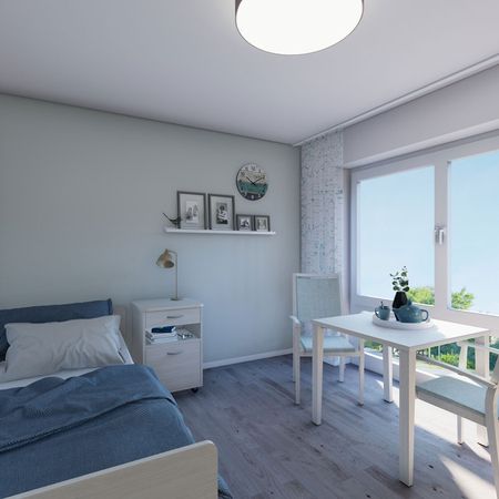 Innenansicht eines kleinen Schlafzimmers im Pflegeheim mit einem Bett, einem Schreibtisch und einem Fenster.